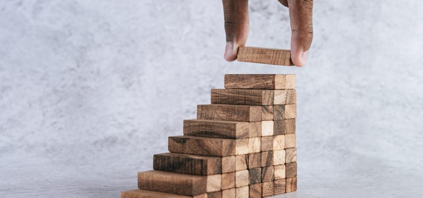 Stacking wooden blocks is at risk in creating business growth ideas.